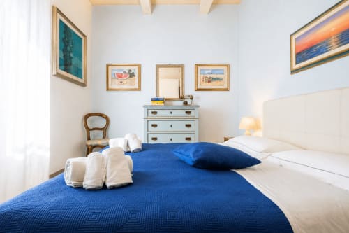 Elegante Suite Matrimoniale ad Al Battistero, Ravenna: biancheria blu, testata crema, cassettone azzurro, opere incorniciate e