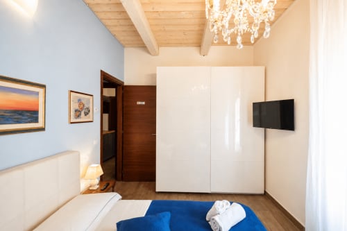 Elegante camera da letto presso Al Battistero Luxury Suite a Ravenna con armadio bianco, TV a schermo piatto e dettagli blu