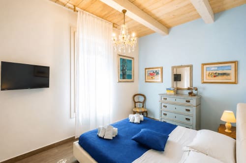 Suite lussuosa di Al Battistero a Ravenna con letto blu, travi in legno a vista e vista sulla città dalle finestre