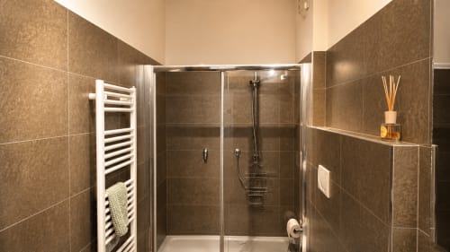 Moderno box doccia con piastrelle marroni e portasciugamani bianco in Suite Matrimoniale presso Al Battistero Luxury Suite