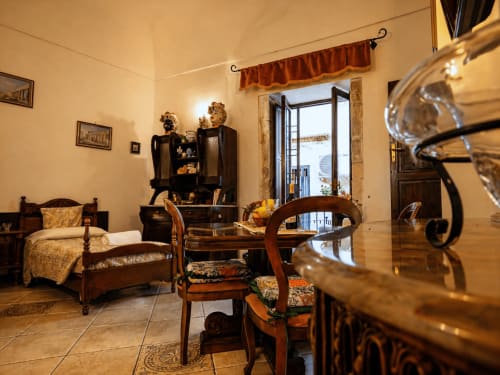 Harmoni Guest House Apartment in Siracusa mit Antiquitäten, Essbereich und Stadtblick durch die Balkontüren