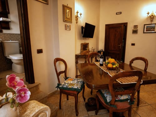 Elegante sala da pranzo ad Harmoni Guest House, Siracusa con tavolo in legno, orchidee e arredamento classico