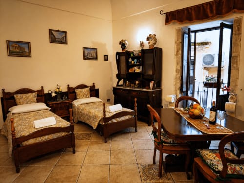 Camera storica dell'Harmoni Guest House a Siracusa, con letti gemelli, mobili antichi e arredamento siciliano tradizionale