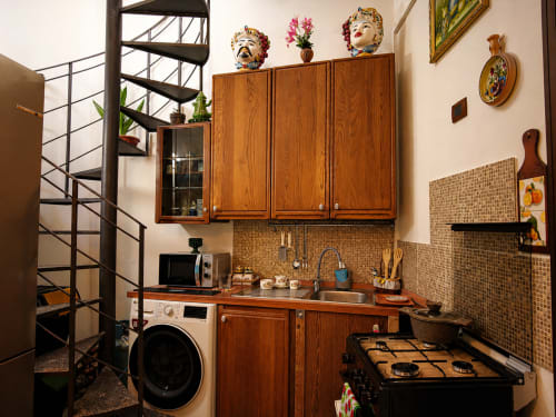 Cucina compatta in Harmoni Guest House, Siracusa con mobili in legno, rivestimento in laterizio e scala a chiocciola