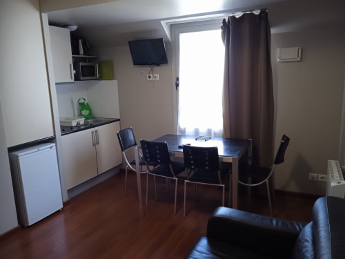 Studio familial at Les Balcons du Sancy with kitchenette, dining table, TV, and brown hardwood floors in Picherande