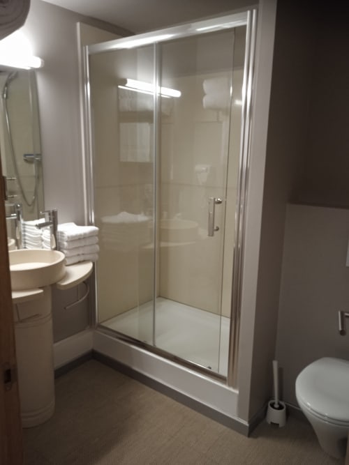 Salle de bain moderne avec douche à l'italienne, lavabo sur colonne et toilettes à l'hôtel Les Balcons du Sancy à Picherande