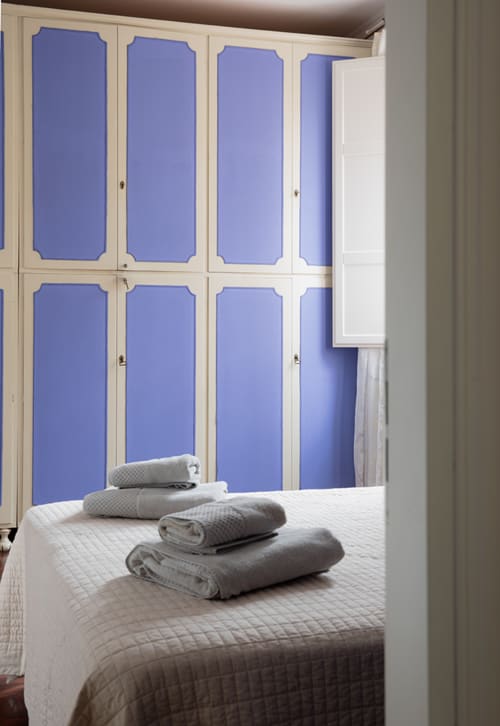 Bedroom with white bed, rolled towels, and blue wardrobe in Cristallo Apartment, Ravenna