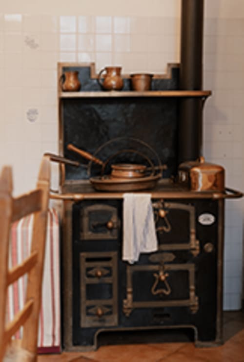 Vintage wood-burning stove in Cristallo Apartment, Ravenna, with copper cookware and fireplace mantel