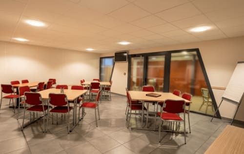 Salle de réunion moderne à l'hôtel La Verriaire à Chanverrie avec chaises rouges, tables et espace de conférence en verre