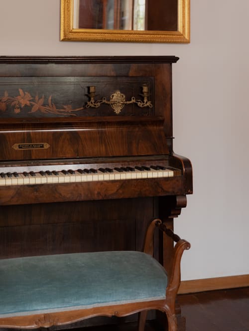 Ornate upright piano with decorative inlay in Cristallo Apartment, Ravenna, elegant wood furniture with bench seat