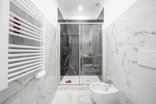 Modern marble bathroom in Rome apartment with walk-in shower, heated towel rail, and circular sink