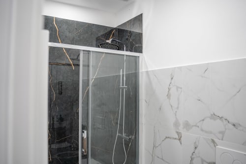 Modern bathroom with marble-effect tiles and dark stone accent wall with gold veining at Colosseum Exclusive Stay, Roma