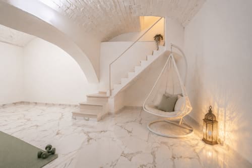 Modern minimalist apartment interior with marble floors, white curved stairs, and a hanging egg chair in Rome luxury hotel