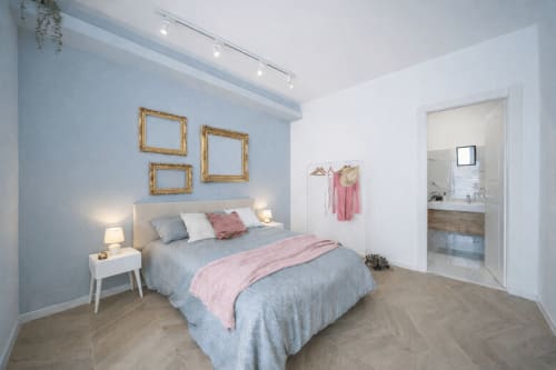Modern bedroom at Colosseum Exclusive Stay Rome with blue walls, queen bed, pink accents, gold frames, and ensuite bathroom