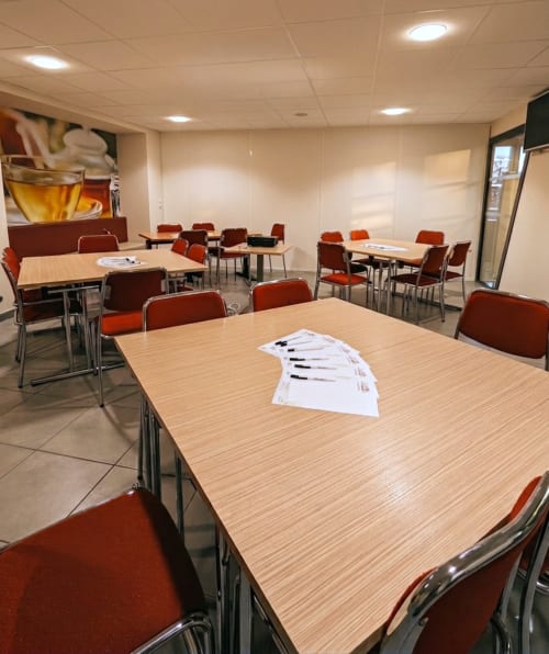 Salle de réunion moderne à l'hôtel La Verriaire à La Verrie avec tables en bois, chaises rouges et éclairage encastré