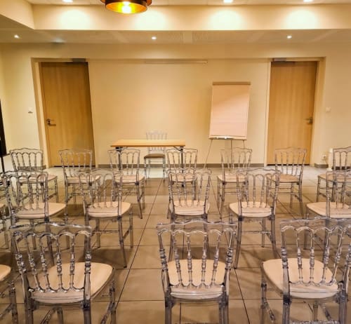 Salle de réunion de l'hôtel La Verriaire avec chaises Chiavari transparentes, tableau papier et portes en bois à Chanverrie