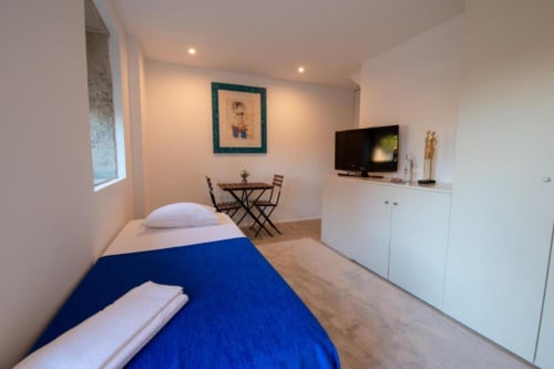 Moderno estúdio em Quinta da Malaposta, Valença com cama azul, TV, escrivaninha e móveis brancos
