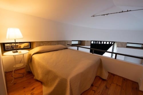 Aconchego no quarto em mezanino do hotel Quinta da Malaposta em Valença, com roupa de cama dourada e piso de madeira