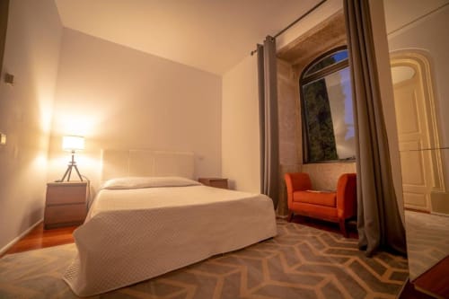 Quarto moderno da Quinta da Malaposta em Valença com cama, poltrona laranja e piso com padrão geométrico