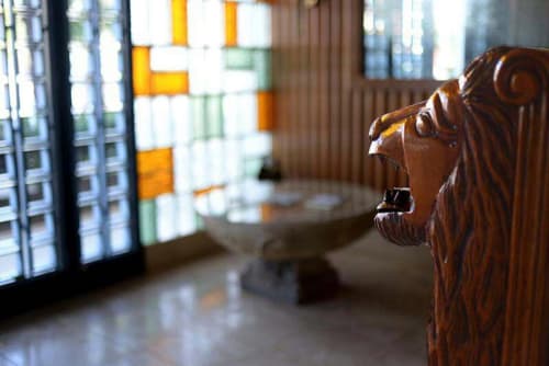 Cabeza de león tallada en madera en el hotel Casa María de Artana, España, con vitrales de fondo