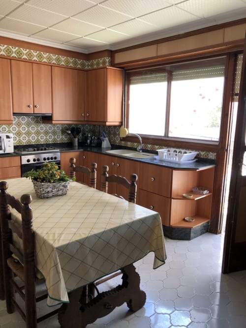 Cocina Casa María en Artana con muebles de madera, azulejos decorativos, mesa de comedor y grandes ventanales con vistas a la terraza