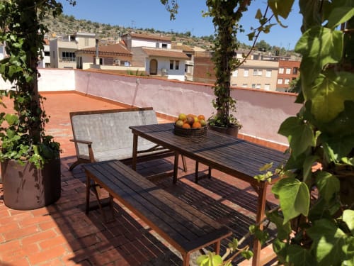 Terraza en la azotea del hotel Casa María en Artana con muebles de madera, frutas frescas y pérgola cubierta de hiedra con vistas
