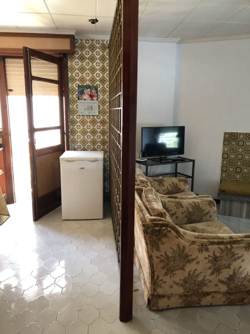 Habitación del hotel Casa María en Artana con sala de estar, sillas florales, TV, kitchenette y papel tapiz estampado