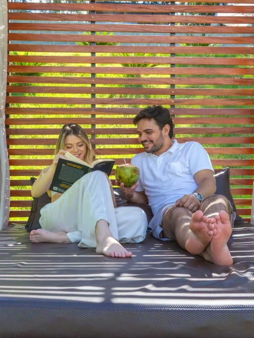 Casal relaxando no deck do Chales do Lago em Caldas Novas, lendo juntos com frutas frescas