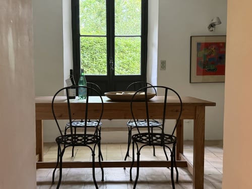 Dining area in La Suite de La Bastide at Domaine de Montlaur with wooden table, black chairs, and garden view