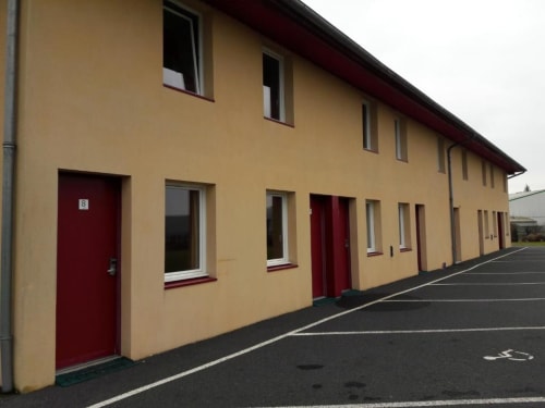 Libre Hôtel exterior in La Vespière, France - yellow building with red doors and windows, accessible ground-floor rooms with