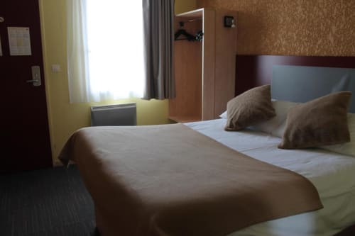 Modern hotel room at Libre Hôtel in La Vespière with twin beds, warm lighting, and contemporary decor