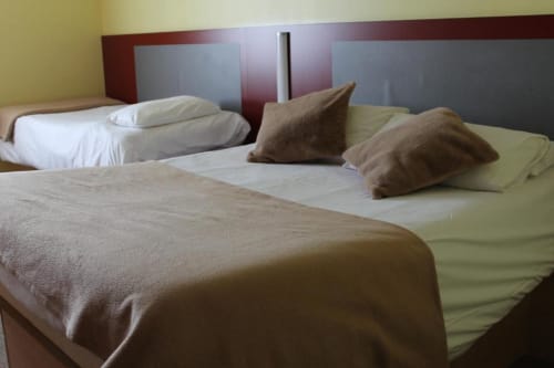 Chambre twin à l'Hôtel Libre avec deux lits, oreillers marron et literie beige à La Vespière, France