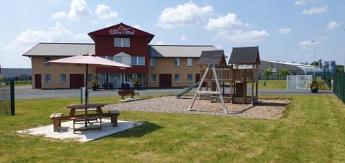 Libre Hôtel in La Vespière features a red-roofed building with playground and picnic areas on green grounds