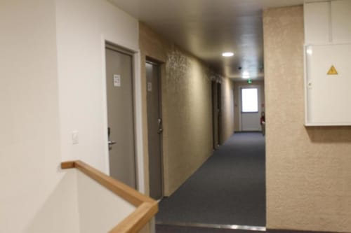 Modern hotel corridor at Libre Hôtel with wooden handrail, multiple doors, and neutral beige decor