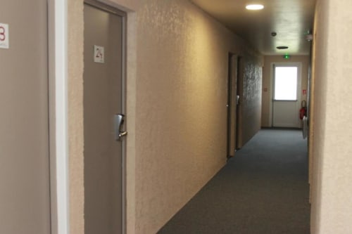 Hallway with numbered doors at Libre Hôtel, a hotel in La Vespière, France with accessible accommodations and garden views.