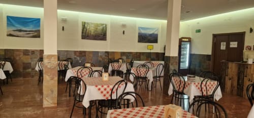 Hotel Atalaya dining room in Guadalupe with red checkered tablecloths, bentwood chairs, landscape artwork on walls, and