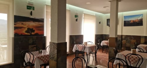 Hotel Atalaya dining room in Guadalupe with checkered tablecloths, black chairs, and landscape artwork on walls