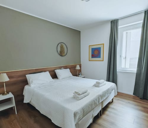 Camera deluxe presso Alloggi Tosca Airport Lodge con letti gemelli, parete accent verde, pavimento in legno e comfort moderni