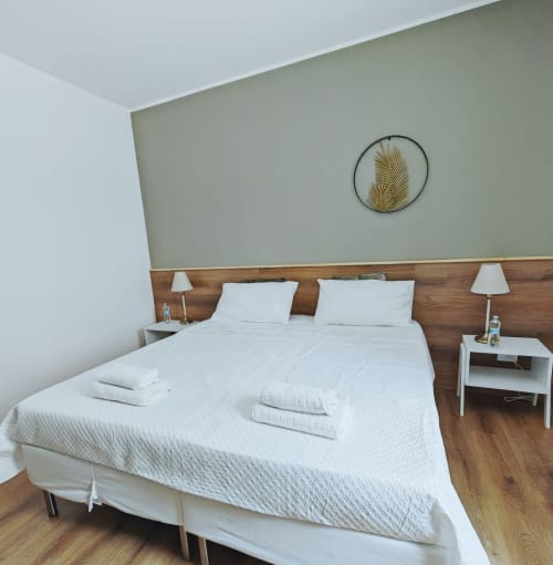 Camera Deluxe moderna presso Alloggi Tosca Airport Lodge con biancheria bianca, testata in legno e arte botanica alle pareti