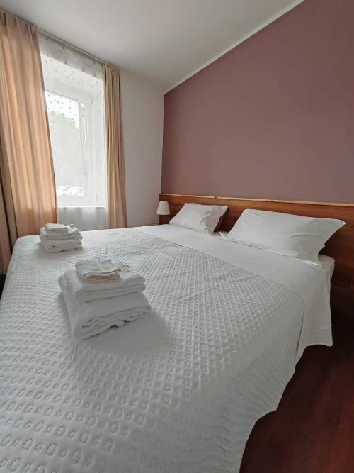 Camera superior di Alloggi Tosca Airport Lodge con letto matrimoniale, asciugamani freschi e parete d'accento color malva