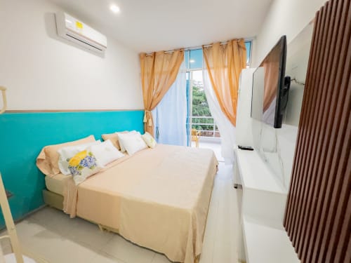 Luminosa habitación doble superior en La Puerta del Angel con cabecero turquesa, ropa de cama crema, balcón con vistas al jardín, aire acondicionado