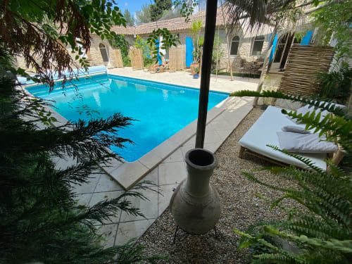 Piscine bleu vif du Patio aux Oiseaux B&B à La Ciotat, France, entourée de transats et bâtiments en pierre