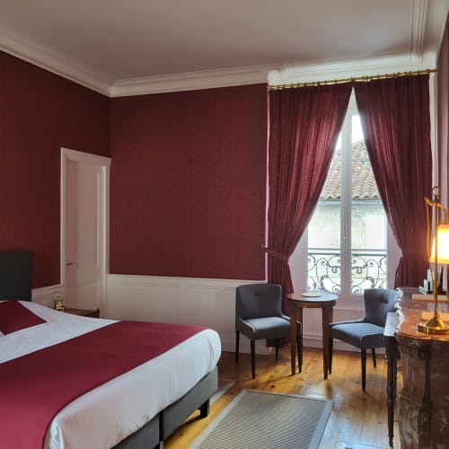 Élégante chambre bordeaux aux Logis des Tourelles à Cognac avec rideaux drapés, parquets et mobilier d'époque