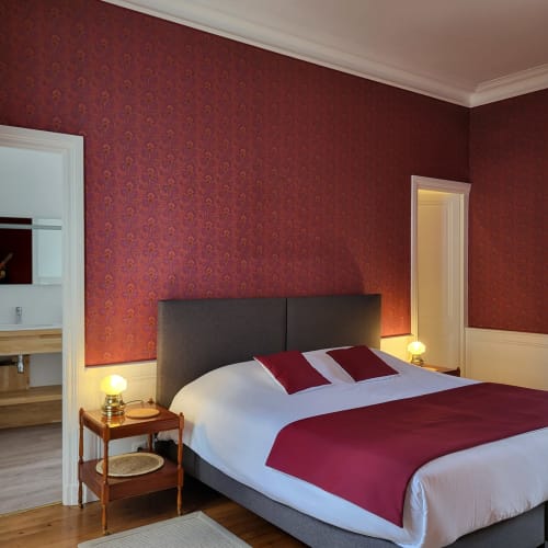 Chambre élégante aux Logis des Tourelles avec papier peint damassé rouge et accents bourgogne