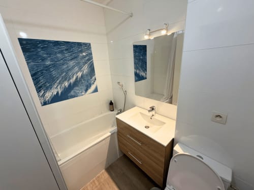 Salle de bain moderne à Horizon Doré avec carrelage blanc, meuble vasque en bois, baignoire, miroir et œuvre d'art vagues océan