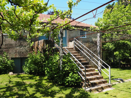 Casarão de pedra com videiras exuberantes na Quinta da Coutada, Portugal, com escadas externas e jardins verdejantes