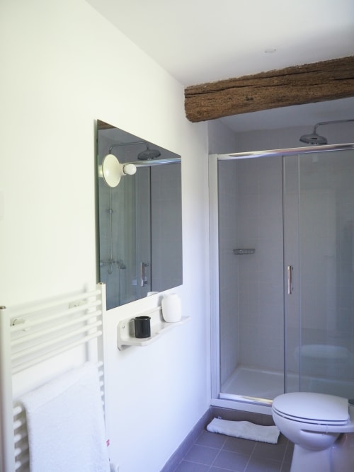 Banheiro moderno do apartamento Quinta da Coutada com box de chuveiro, vaso sanitário, toalheiro aquecido e espelho com iluminação