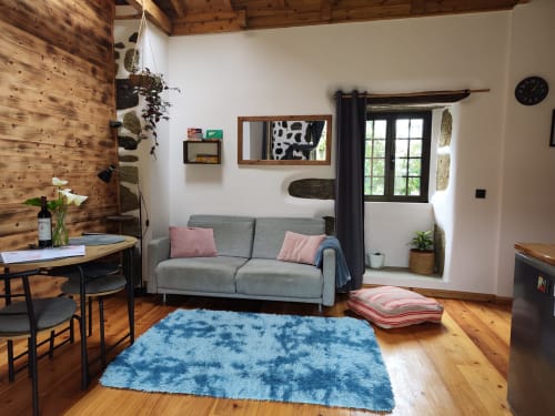 Cozy living area at Casa Rosa villa in Fajazinha with gray sofa, blue rug, wooden floors, and garden view access