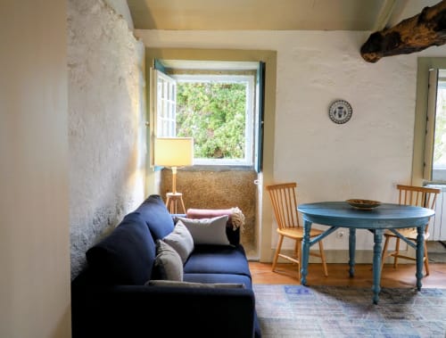 Aconchegante sala de estar em Quinta da Coutada com sofá azul marinho, mesa de jantar azul, cadeiras de madeira e vista para o jardim