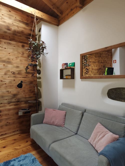Cozy living room in Casa Rosa villa at Casas Florescer with gray sofa, wooden walls, hanging plant, and garden view mirror